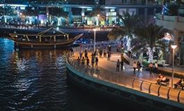 Gece ışıklandırılmış binalar ve göl üzerinde tekne