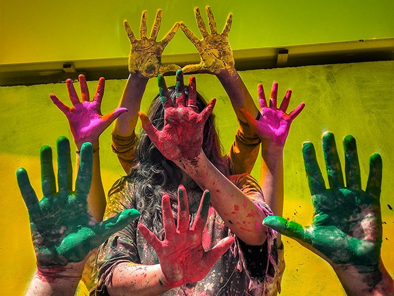 Holi festivalinde elleri renkli boyalar ile boyanmış insanlar ellerini gösteriyor