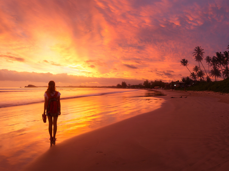 Negombo sahilinde gün batımında yürüyen kadın turist