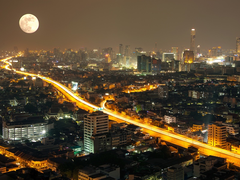 Gece dolunay altında Bangkok şehrinin binaları ve şehrin içinden geçen yolu ile kuş bakışı görüntüsü