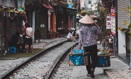 Dar bir sokaktan geçen tren yolu ve arkası dönük yerli adam Hanoi